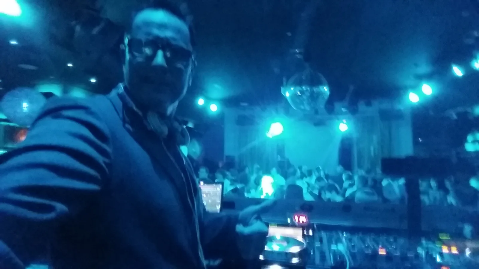 DJ Rafael pinchando en fiesta con iluminación cian