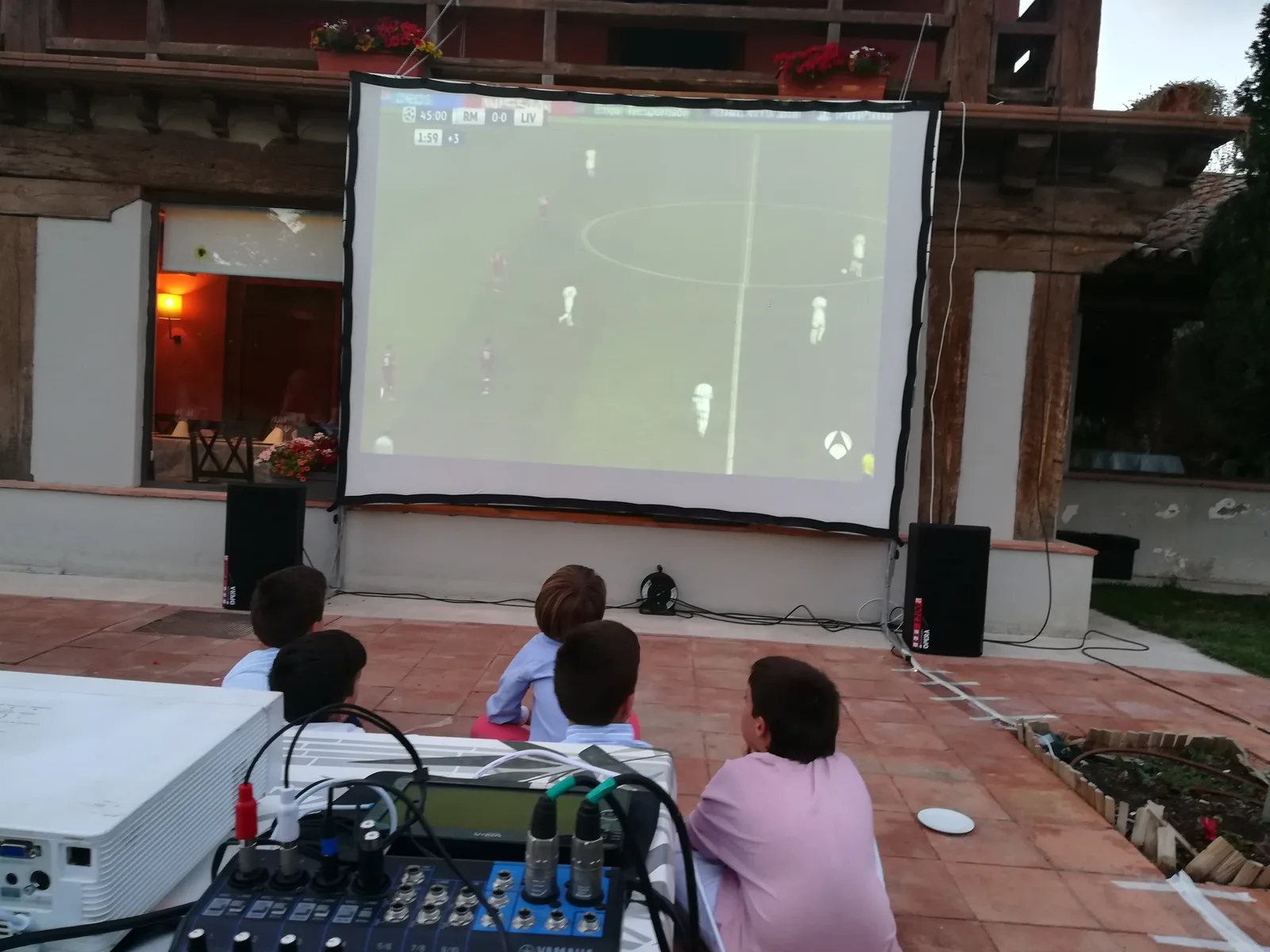 Niños viendo fútbol en pantalla gigante exterior